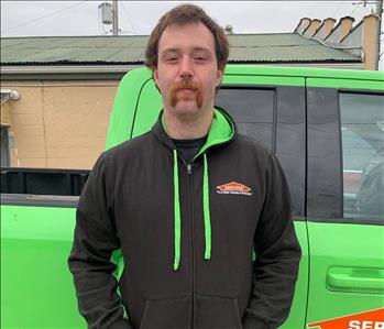 side of bright green truck with team member, male with brown hair